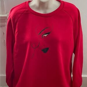 Red fleece sweater with woman’s face and an eye, size L bohemian wearable art